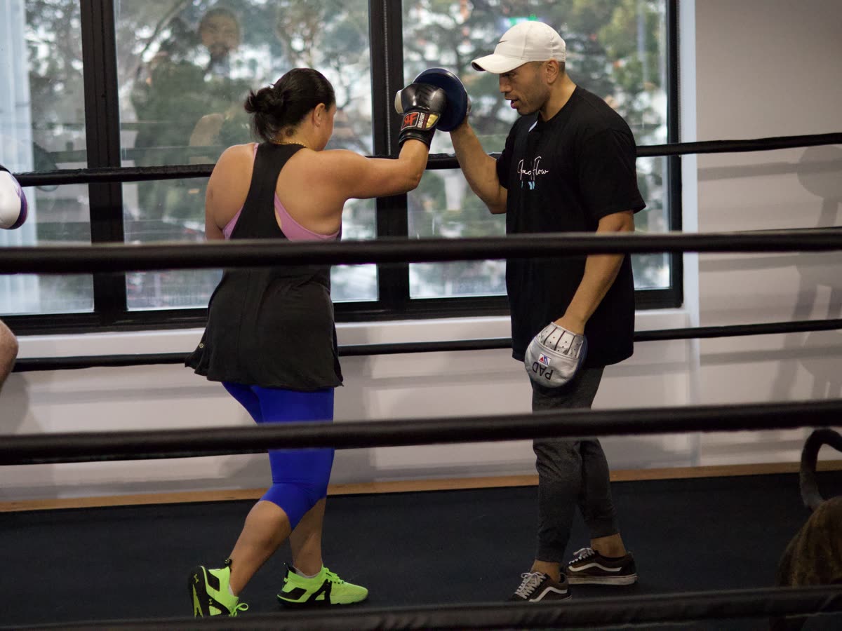 Coach holding pads for a beginner in the boxing ring